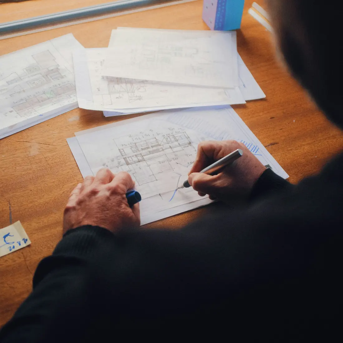 A person at a desk annotating printed documents with a pen.