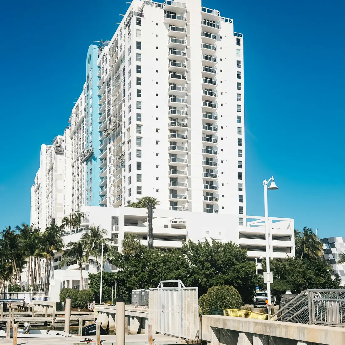 A white Florida condominium tower on the waterfront, palms in the foreground.